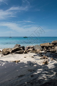 海滩上的岩石和阴影在圣卢西亚海外有渔船的滩上反射天空蓝色的图片