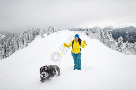 步行雪鞋走一只狗和他的情妇独自在山上雪多的可爱图片