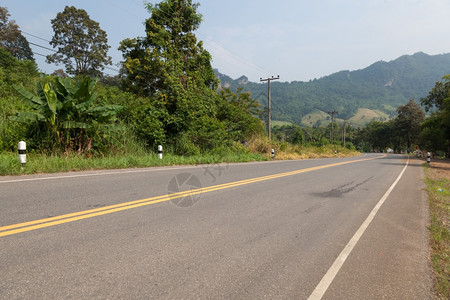 驾驶秋天爬坡道山上的路横穿坡沿的树丛图片