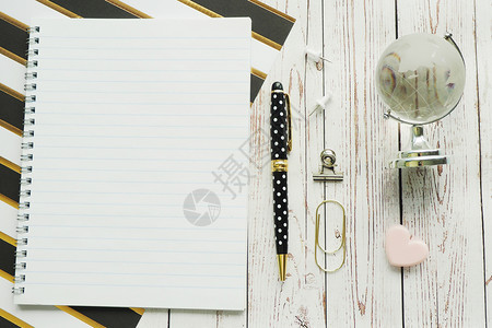 弹簧钢笔康乃馨剪贴和玻璃球笔记本带条纸和灰色木背景的玻璃球一种复制金子图片