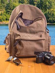 配件木制桌上的背包照相机和太阳镜木制背景上的相机和眼镜冒险一种图片