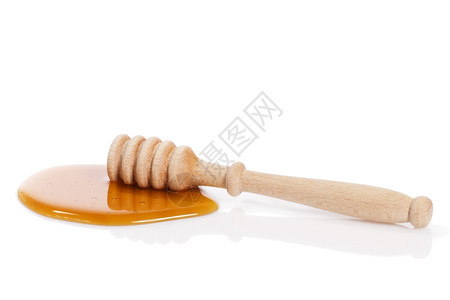 蜂蜜杓子在水坑里干杓子在白色背景的蜂蜜水坑里滴甜的新鲜图片
