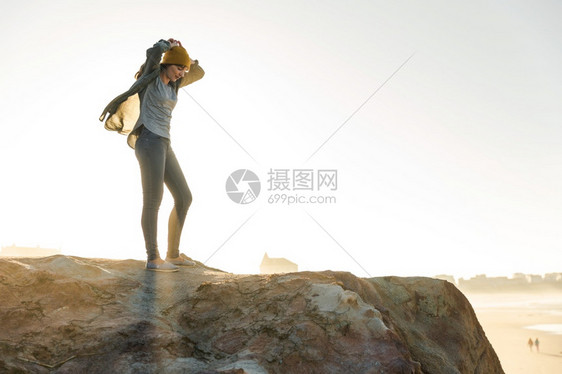 美丽的女人在海滩悬崖上戴着黄色的帽子游客女孩士图片