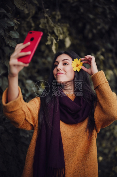 女人用手机拍自头发上插着花朵电话年轻的漂亮图片