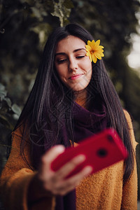 女人用手机拍自头发上插着花朵漂亮的森林女图片