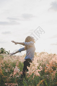 乐趣常设户外年轻美丽的女士站在草原上举起双臂在空中露出青草地日落时与大自然相享受图片