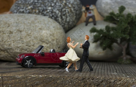 摄影师成人小迷你物在婚礼上跳舞靠近一辆红色的轿车玩具乐趣图片