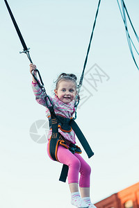 小可爱笑的女孩跳在蹦床上玩得开心季节行动可爱的图片