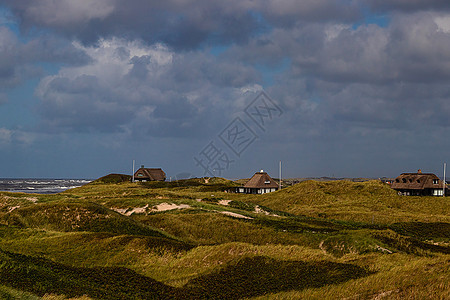 丹麦沙丘之间云的层堆积恢复海岸图片