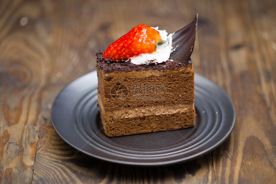 蒸着棕色的苦恼烧焦木材碟中巧克力蛋糕的切片图片