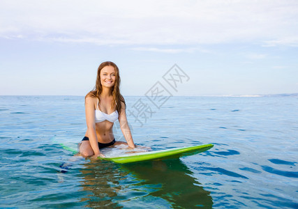 坐在冲浪板上等待海浪的美女图片