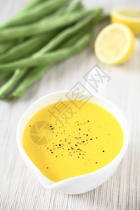 一种Holandaise酱油是法国烹饪的基本调料在一条配有土黑胡椒的沙拉船上服务后面加柠檬和生青豆用自然光拍攝选择焦点图像中的焦图片