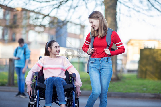 白种人户外微笑在离开高中时和朋友交谈的轮椅女青少年孩在离开高中时与朋友交谈图片