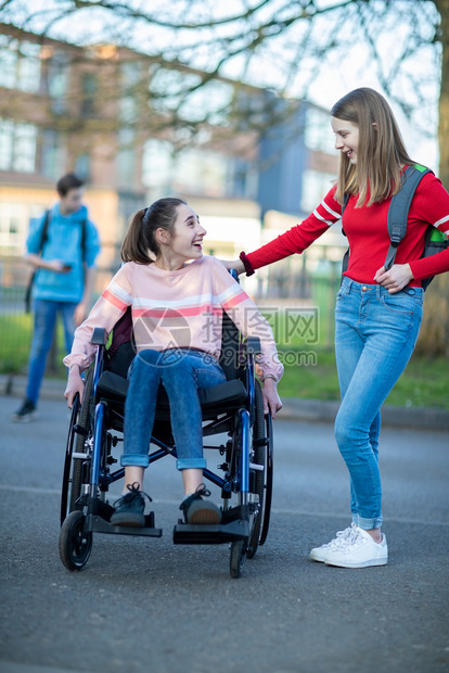 垂直的学校白种人在离开高中时和朋友交谈的轮椅女青少年孩在离开高中时与朋友交谈图片