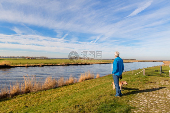 荷兰的Eem河地貌景观有老年男子和狗户外卡纳尔自然图片