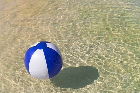 采取漂浮在水面的可充气蓝色和白海滩球假期夏天图片