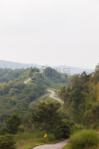 天空的自然山上弯曲道路在山上拐弯两边都有树的山上公路图片