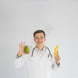 水果案子快乐的持有鳄梨香蕉手的快乐医生图片