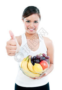 漂亮的营养可爱一位健身妇女拿着一篮子水果在白背景上举起拇指手势的肖像图片