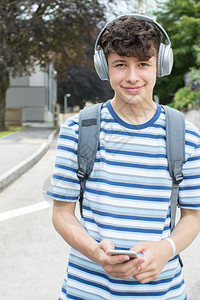 校外青少年学生在院大楼外的听音乐肖像移动人们耳机图片