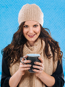 冬天相片中一位美丽的黑发女裹着温暖的围巾和帽子喝着热咖啡或巧克力女饮料图片