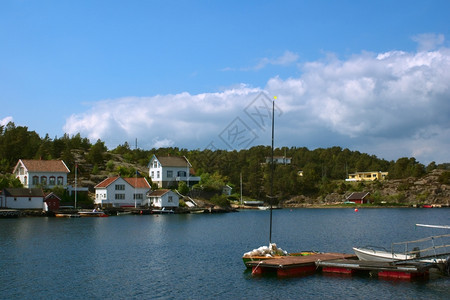 沿着挪威南部岸林戈尔村内载有帆船和白房子的喷气艇和白色房屋乡村的图片