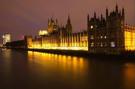 河边议会的众院在晚上点燃了灯光黄亮照耀着泰晤士河屋图片