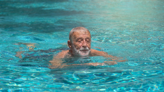 锻炼快乐的老年男子在户外游泳池游泳图片