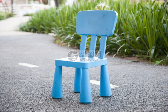 蓝塑料椅子在地板上的位置在树丛后面的公园中行走座位现代的花园图片
