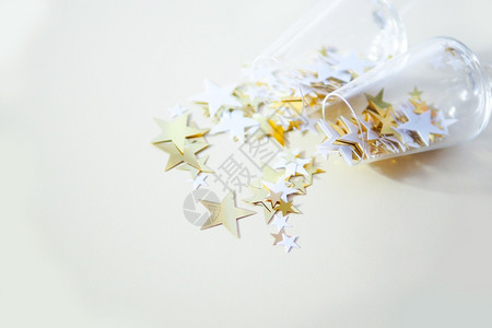 工艺桌子上两副眼镜和漂落的彩色白星和蜜蜂背景上的金色星乐趣闪耀图片