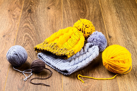 纺织品温暖的木背景上线和编织帽圆球羊毛图片