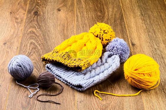纺织品温暖的木背景上线和编织帽圆球羊毛图片