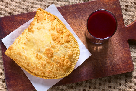 玻璃利维亚传统零食叫做派斯特尔深炸糕饼盛满奶酪的薄饼配有木板上的紫玉米饮料Api与天然光相照小吃传统的背景图片