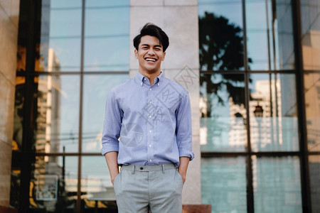 办公室城市中笑的亚洲青年商人肖像看着摄影机一个快乐友善的人工作快乐图片