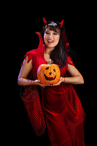 万圣节美丽感的年轻女子拿着南瓜穿红魔服装杰克女节假日图片