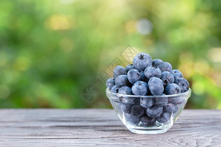 浆果木桌上玻璃碗里的蓝莓夏季静物木桌上玻璃碗里的蓝莓收成熟图片
