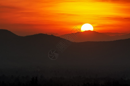 黄色的明亮日落时太阳美丽在山上向日落红色的图片