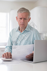 坐着使用笔记本电脑计算家庭财政的焦虑健壮男子垂直的成熟图片