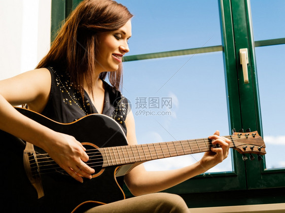 女照片中一位微笑着的女人在她20多岁的晚期她用一个大窗户弹吉他黑色的20多岁图片