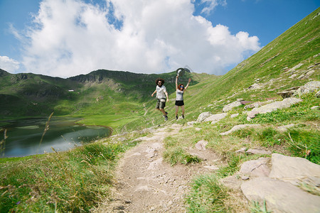 冒险年轻夫妇在大山谷中跳跃背景是冰川湖在乌埃斯卡的奥德萨自由概念徒步旅行奥尔德萨图片