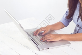 吸引人的亚洲桌子在工作场所的笔记本电脑键盘上打手字图片