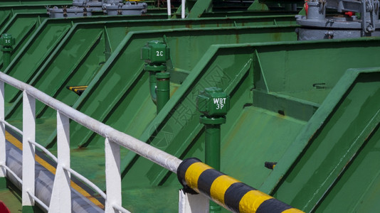 技术绿色储油罐的金属管道与原油轮上白色护栏的废油罐侧面视图甲板机械的图片
