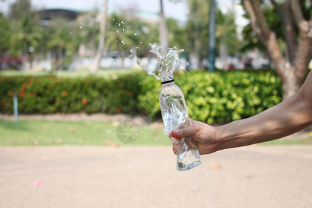 人们一个男的手拿着一瓶饮用水洒在花园里饮料夏天图片素材