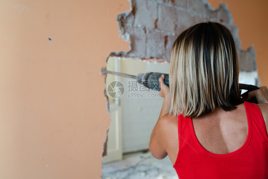 妇女背视用充气锤子钻破其公寓的墙壁准备翻新大锤机PHA准备好后退破坏图片