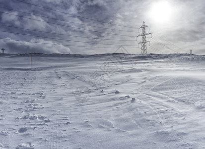 晴天冬日在山上的高压柱冬天电缆图片