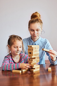 学习小女孩龄前儿童及其姐与木棍玩耍游戏具比布林斯一起坐在家里的办公桌旁坐在家里着有趣的图片