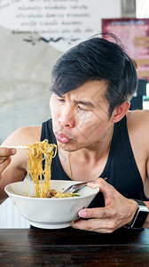 可口亚洲男人在食堂里吃泰国面条球辛辣的图片
