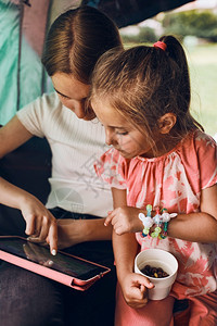 旅行孩子们闲暇在暑假期间两个女孩姐妹在露营儿童帐篷中度过家庭时间她们利用平板电脑在网上玩游戏姐妹姊们在夏假期间用平板电脑在网上玩图片