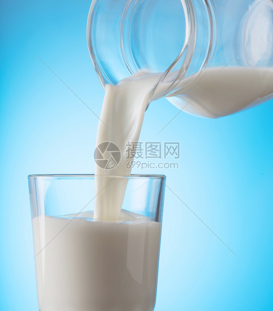 滴乳制品液体健康天然食物的理念从水壶倒到蓝底杯子上健康的自然食物牛奶从水壶倒到蓝底杯子上图片