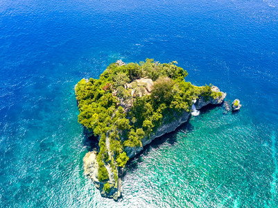 一座小岩石岛由来自水的丛林和几间小棚屋在大海落基岛与Huts空中观之间的树丛铺设着地势茂密的阶梯印度尼西亚翠假期图片
